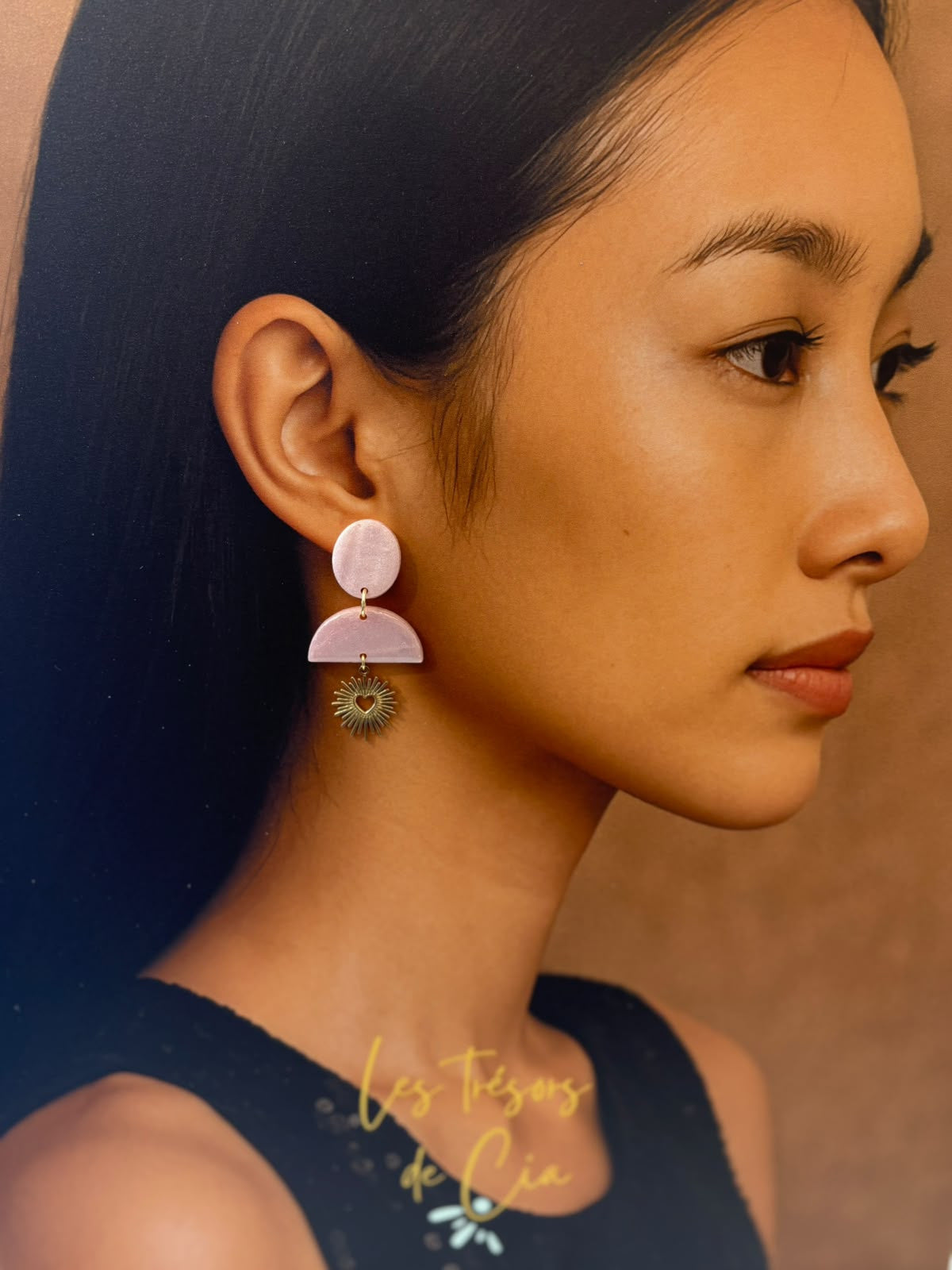 Boucles d'oreilles en argile rose poudré nacré, puce ronde et demi-lune, avec un cœur doré ajouré entouré de rayons suspendu en dessous.