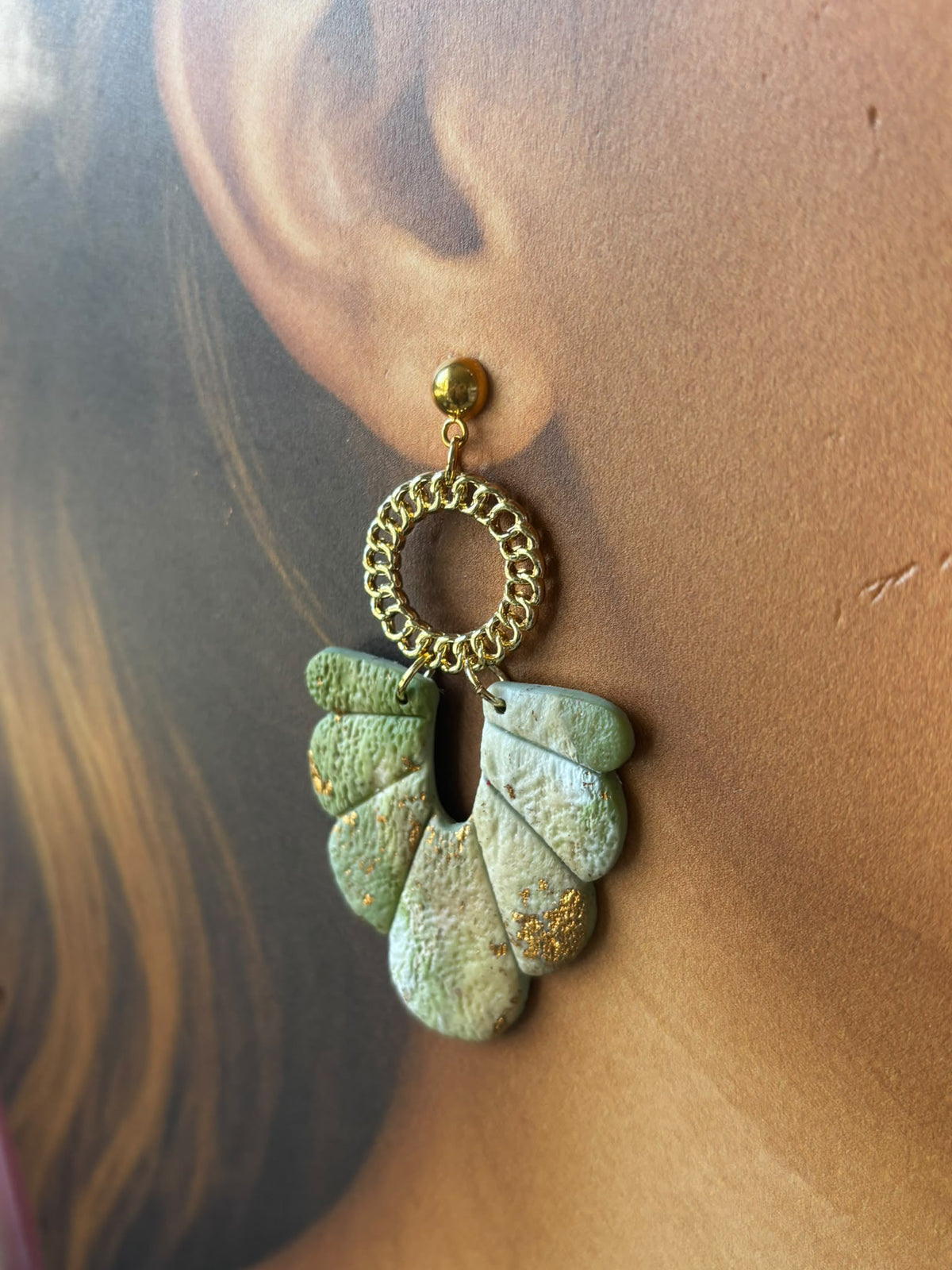 Gros plan sur la boucle d'oreille Janet vert d'eau : puce dorée, anneau doré texturé et éventail d'argile aux éclats dorés