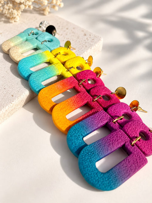 Les quatre coloris des boucles d'oreilles RAINBOW D'AUTOMNE en argile polymère alignés, dégradés bleu, jaune, orange et fuchsia