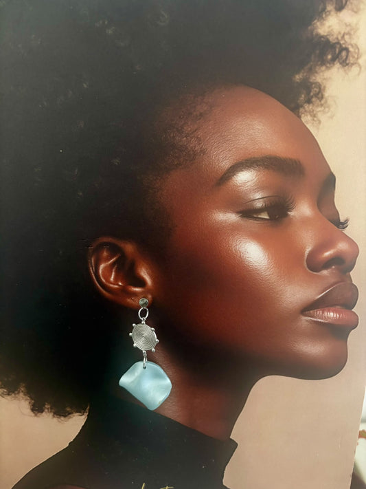 Boucles d'oreilles spirale argentée et galet bleu nacré portées à l'oreille