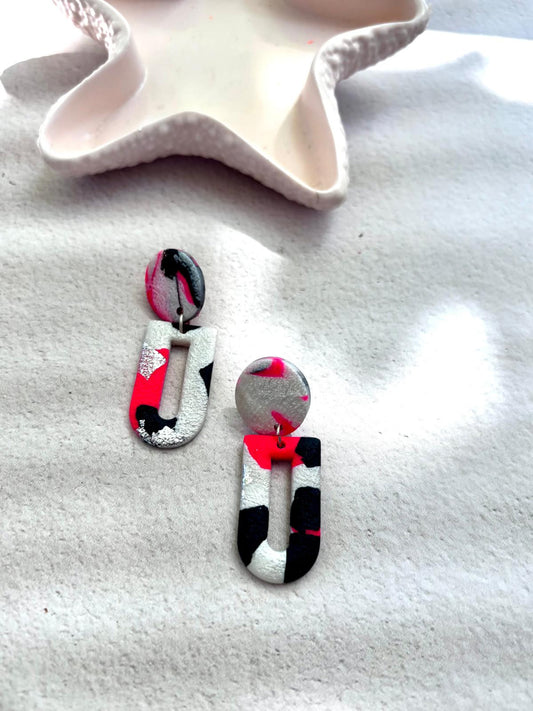 Boucle d'oreille en arche évidée rose fluo, noir et argent métallisé en larges aplats contrastés, montée sur une puce ronde