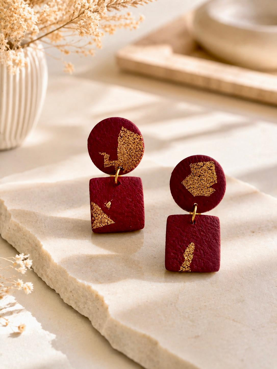Boucles d'oreilles bordeaux mat parsemé d'éclats de feuille dorée, puce ronde surmontant un carré aux angles arrondis