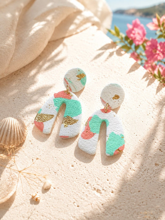 Boucle d'oreille arche large en argile polymère blanche texturée, tachetée de menthe et de corail, avec des éclats de feuille dorée et une puce ronde en haut.